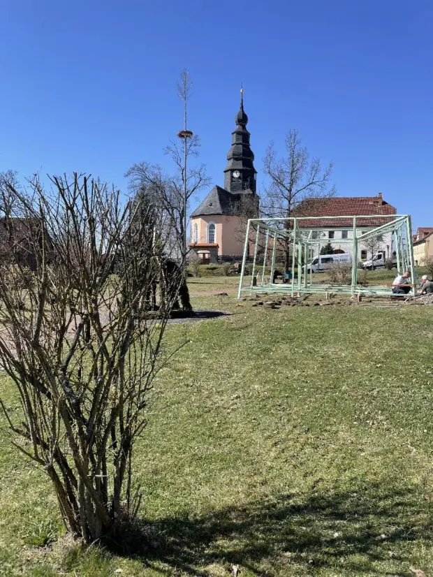 Wiese mit dem Gerüst "HORST" im Hintergrund die Kirche von Dreba